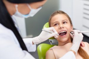 A hygienist examining a child’s teeth.